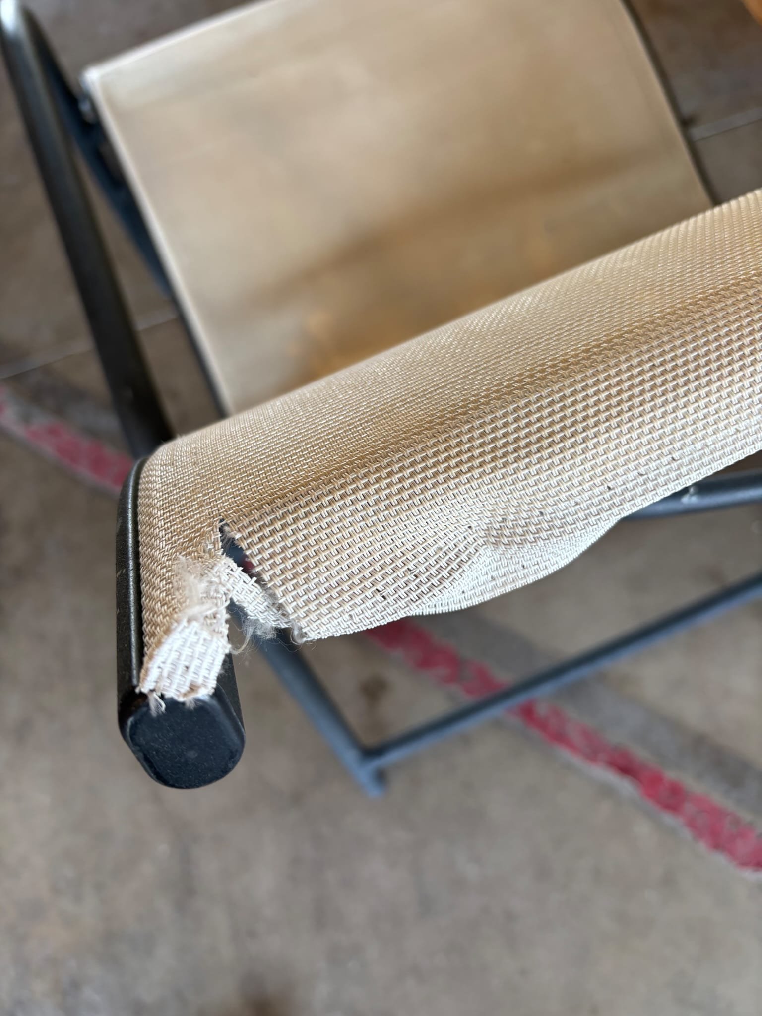 Torn outdoor chair sling fabric before repair